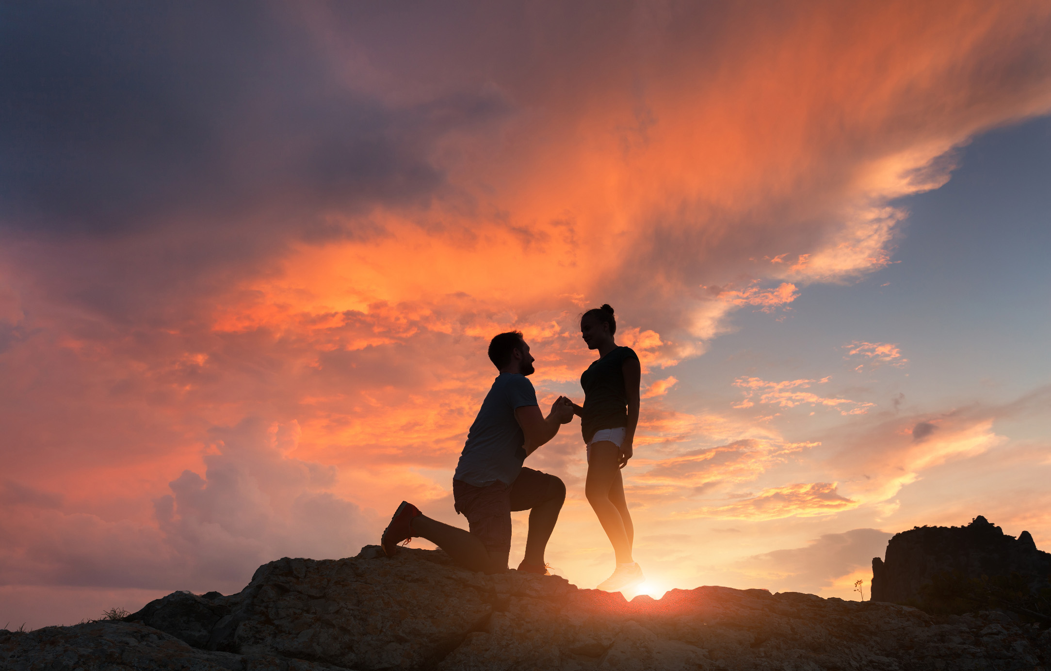 man proposing to a woman on a mountain during sunset hours