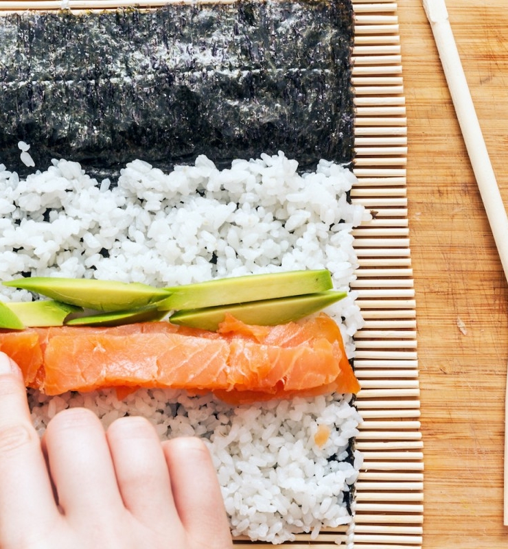 sushi rolls being rolled by hand