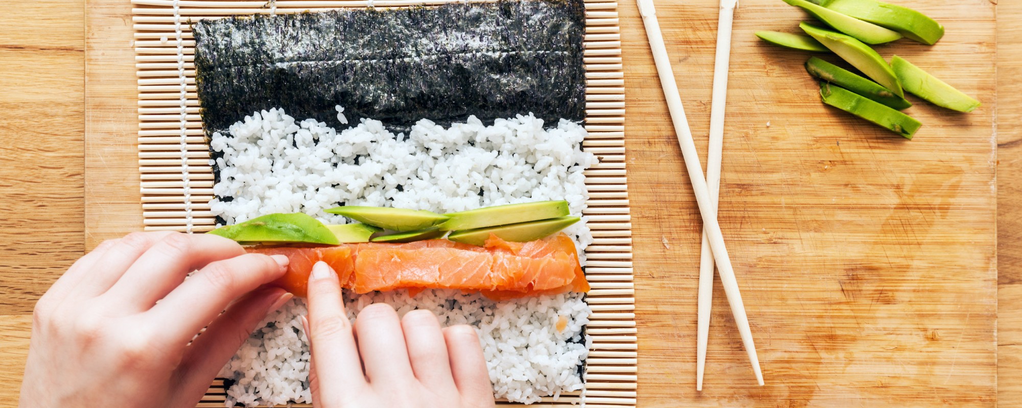 sushi rolls being rolled by hand